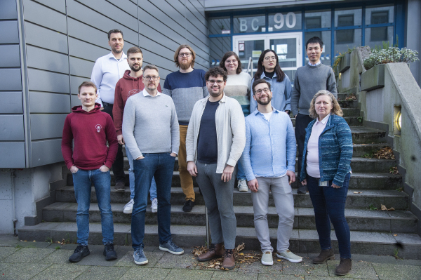 Das Team des Fachgebiets steht vor einem Gebäude und lächelt in die Kamera