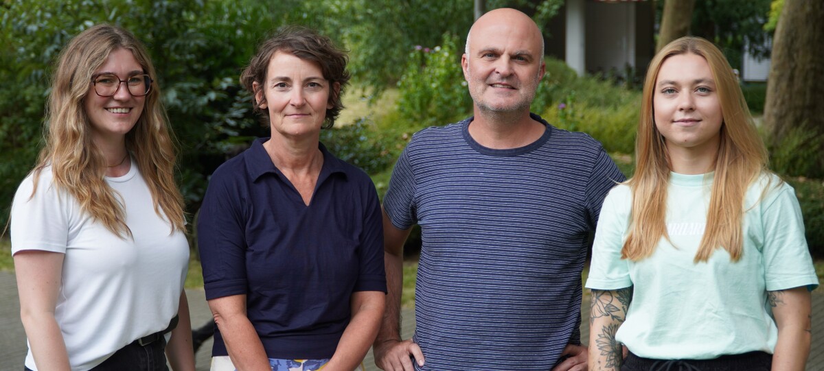 Photo of the four research team members in front of a blurred background of greenery